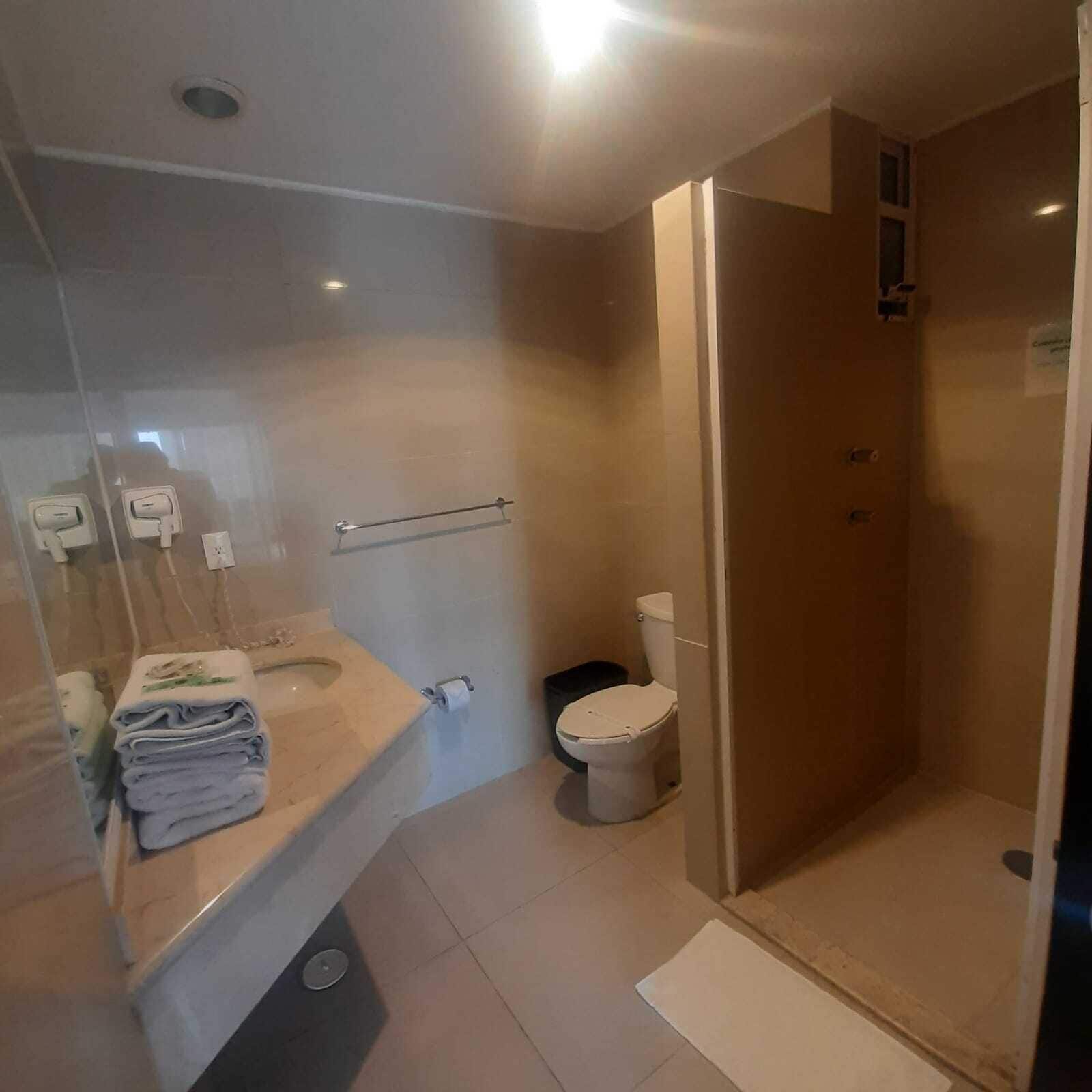 Ein modernes Badezimmer mit Duschkabine aus Glas, Toilette und Waschbecken mit Handtüchentürmchen.