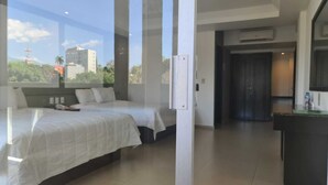 Habitació d'hotel moderna amb dos llits, una finestra gran i vista a la ciutat.