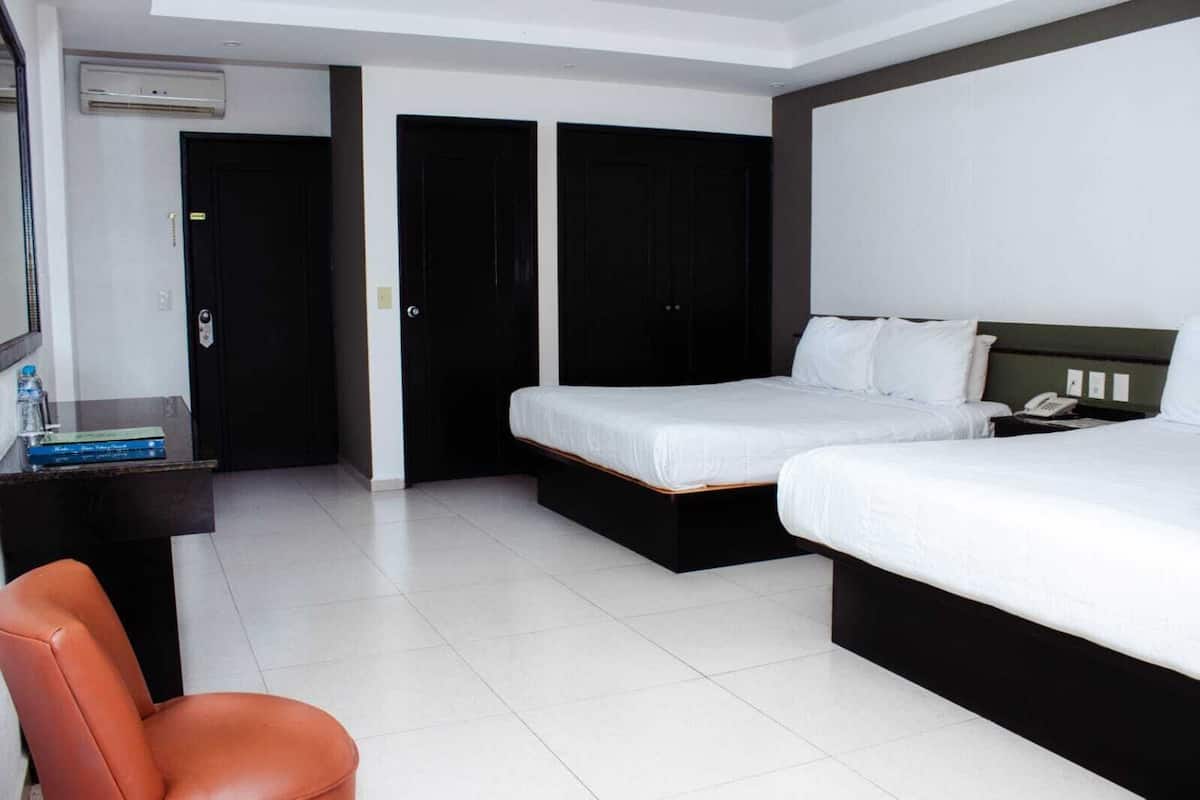 A hotel room with two beds, a desk, a chair, and a wardrobe.