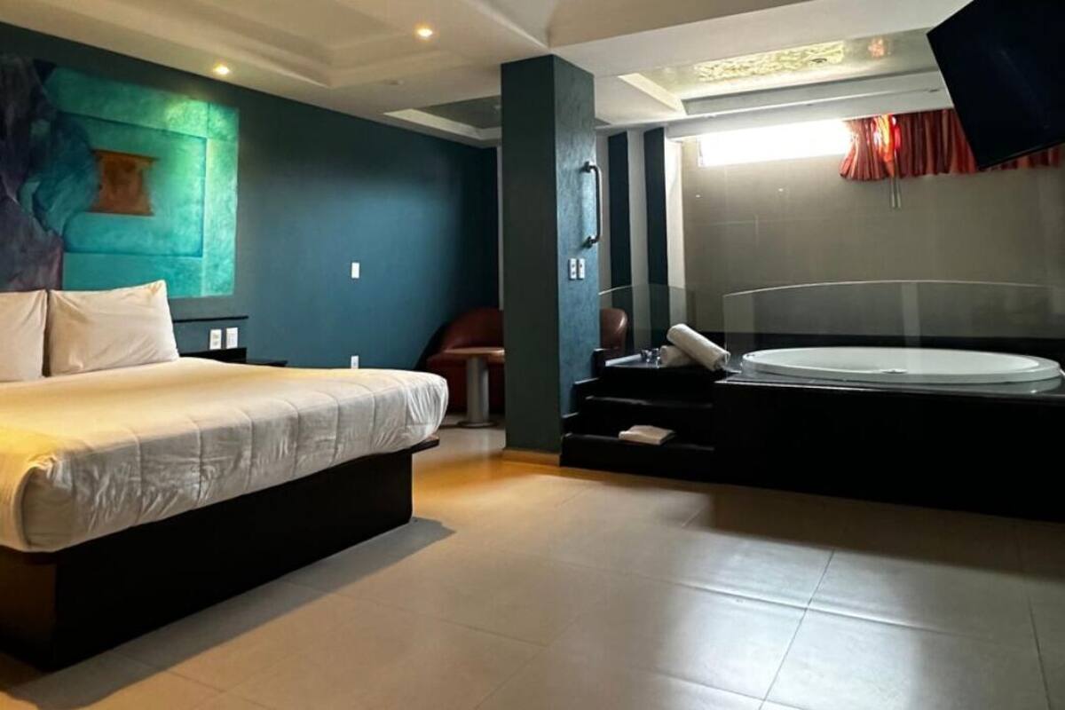 A modern hotel room with a large bed, a separate seating area, and a bathtub.