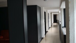 Un passadís amb sòl de rajola, parets blanques i pilars negres.