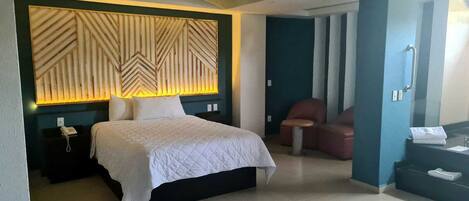 A hotel room with a bed, a chair, a desk, and a bathroom.
