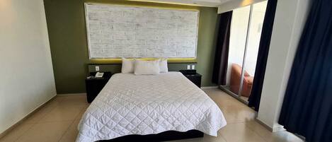 A hotel room with a large bed, a nightstand, a wall-mounted TV, and a sliding glass door.