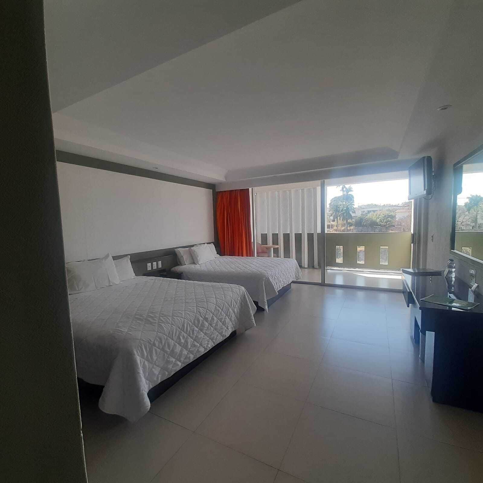 Ein Hotelzimmer mit zwei Betten, einem Schreibtisch und einem Balkon mit Blick.