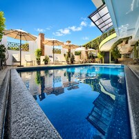 Una piscina al aire libre, sombrillas, sillones reclinables de piscina