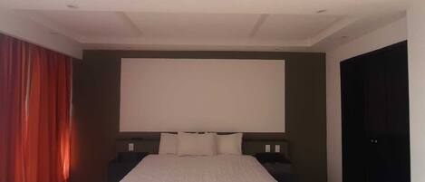Un dormitorio moderno con una cama grande, un televisor de pantalla plana y un armario de color oscuro.