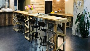 A modern bar area with wooden stools and a long counter. - GUEST HOUSE MASAGO - Hostel (Urakawa)
