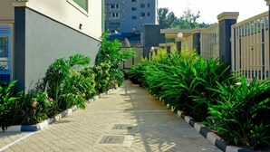 A pathway flanked by lush greenery and a gated entrance to a residential building. - Greendale Apartments (Kampala)