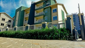 A multi-story residential building with balconies, a paved walkway, and lush greenery. - Greendale Apartments (Kampala)