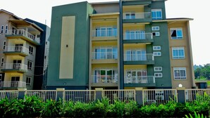 A multi-story residential building with balconies, a gated entrance, and a well-maintained garden area. - Greendale Apartments (Kampala)