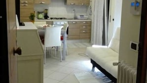 Um espaço compacto para viver, com cozinha compacta, área de refeições e sofá.