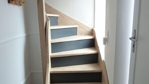 Una escalera de madera con un suelo oscuro al final.