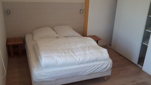 Un dormitorio con cama, dos mesitas de noche y suelo de madera.