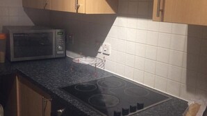 A kitchen with a microwave, stove, and white tiled backsplash. - King Size Bed in Large Room Kew Riverside Apartment  (Richmond)