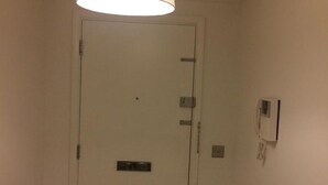 A white door with a small vent, a light switch, and a telephone mounted on the wall. - King Size Bed in Large Room Kew Riverside Apartment  (Richmond)