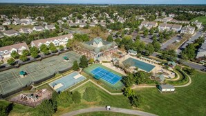 An aerial view of a residential area with multiple houses, a tennis court, and a swimming pool. - Bear Trap Dunes * 4BR Lovely Townhouse End Unit (Ocean View)