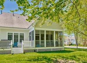 A house with a covered porch, a lawn, and a tree.