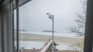 Vista des d'una finestra sobre una platja amb un cotxe estacionat al carrer.