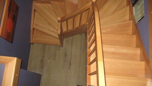 Una escalera de madera con barandilla que lleva a un rellano con una pared azul y un cuadro enmarcado.