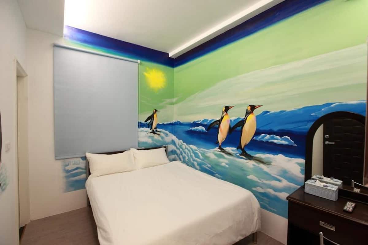 A bedroom with a bed, a dresser, and a wall mural of penguins on ice.