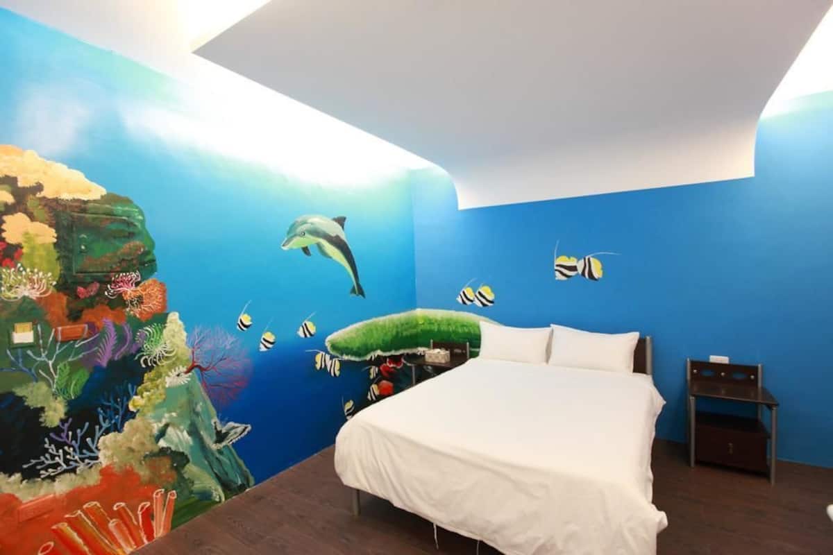A bedroom with a mural of an underwater scene, a bed, and a nightstand.