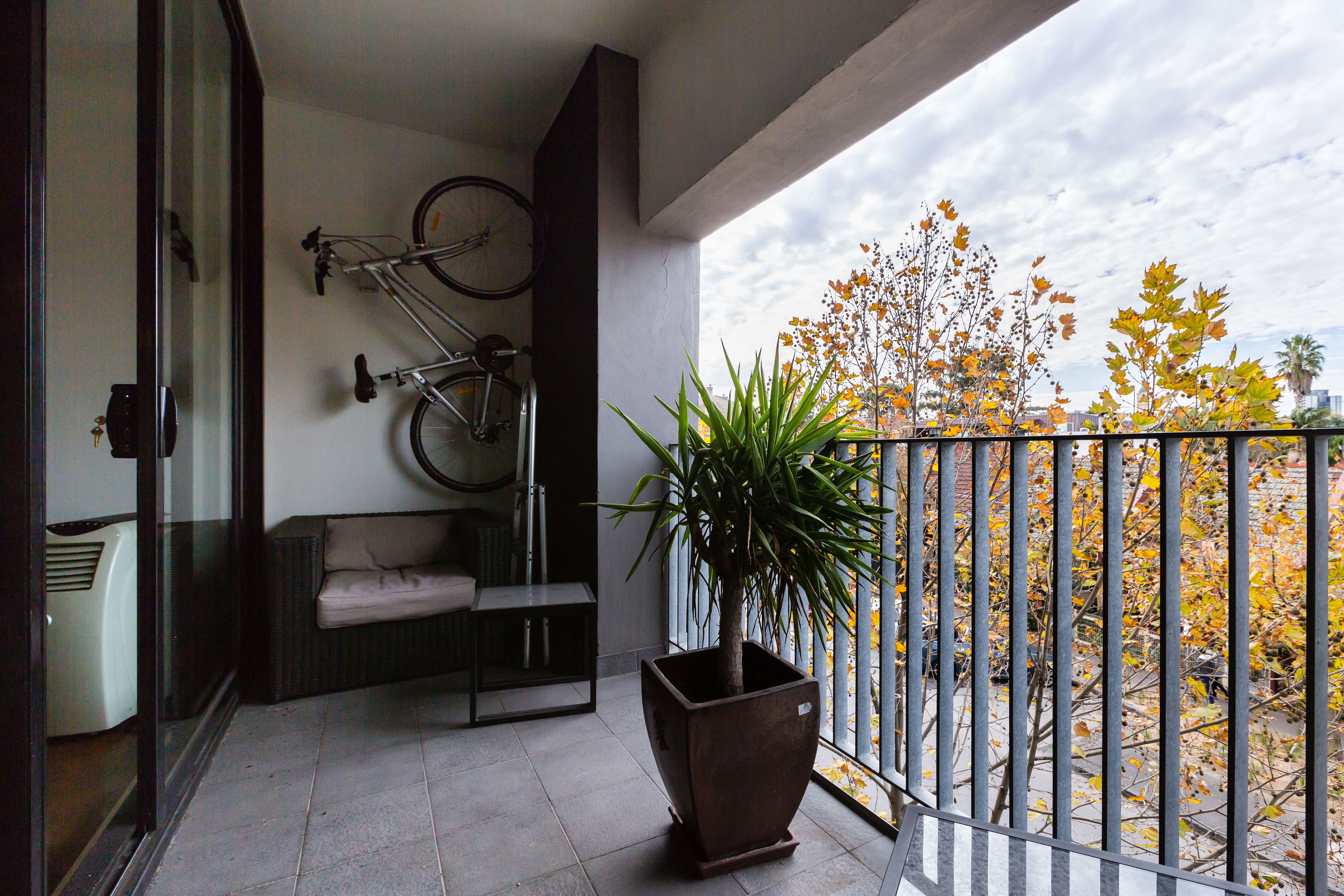 A balcony with a potted plant, a bicycle, and a sofa.