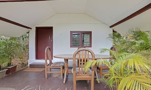 Relax in a charming outdoor space with a round table and comfortable seating for four, surrounded by lush greenery.