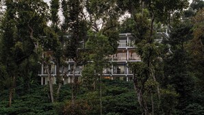 A multi-story building surrounded by dense greenery. - Itsy Hotels Jammabane Cottage (Somvarpet)