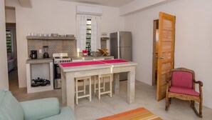 A compact kitchen with a gas stove, a refrigerator, and a dining table with stools. - Comfortable Villa with sea view  (San Pedro)