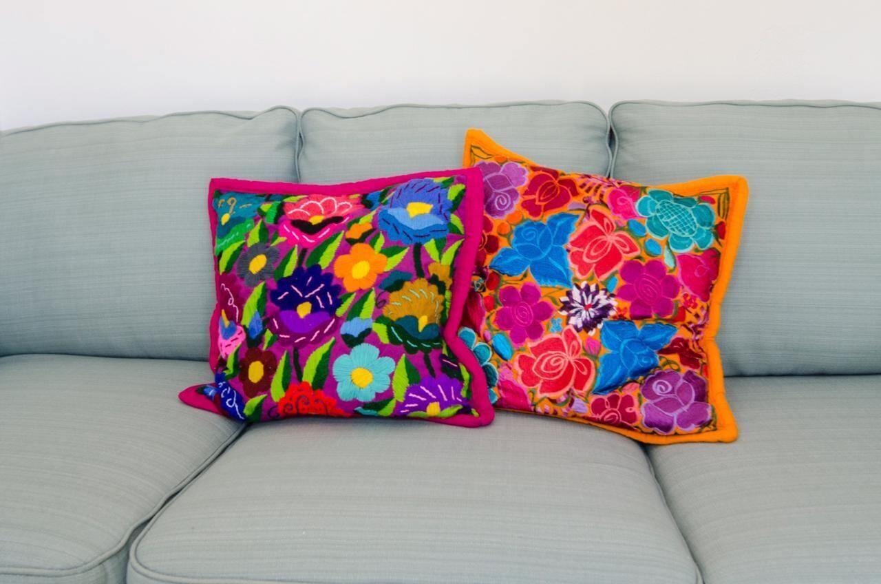 Two colorful pillows on a light grey sofa.
