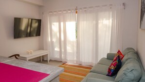 A living room with a sofa, a TV mounted on the wall, a small table with candles, and a colorful striped rug. - Comfortable Villa with sea view  (San Pedro)