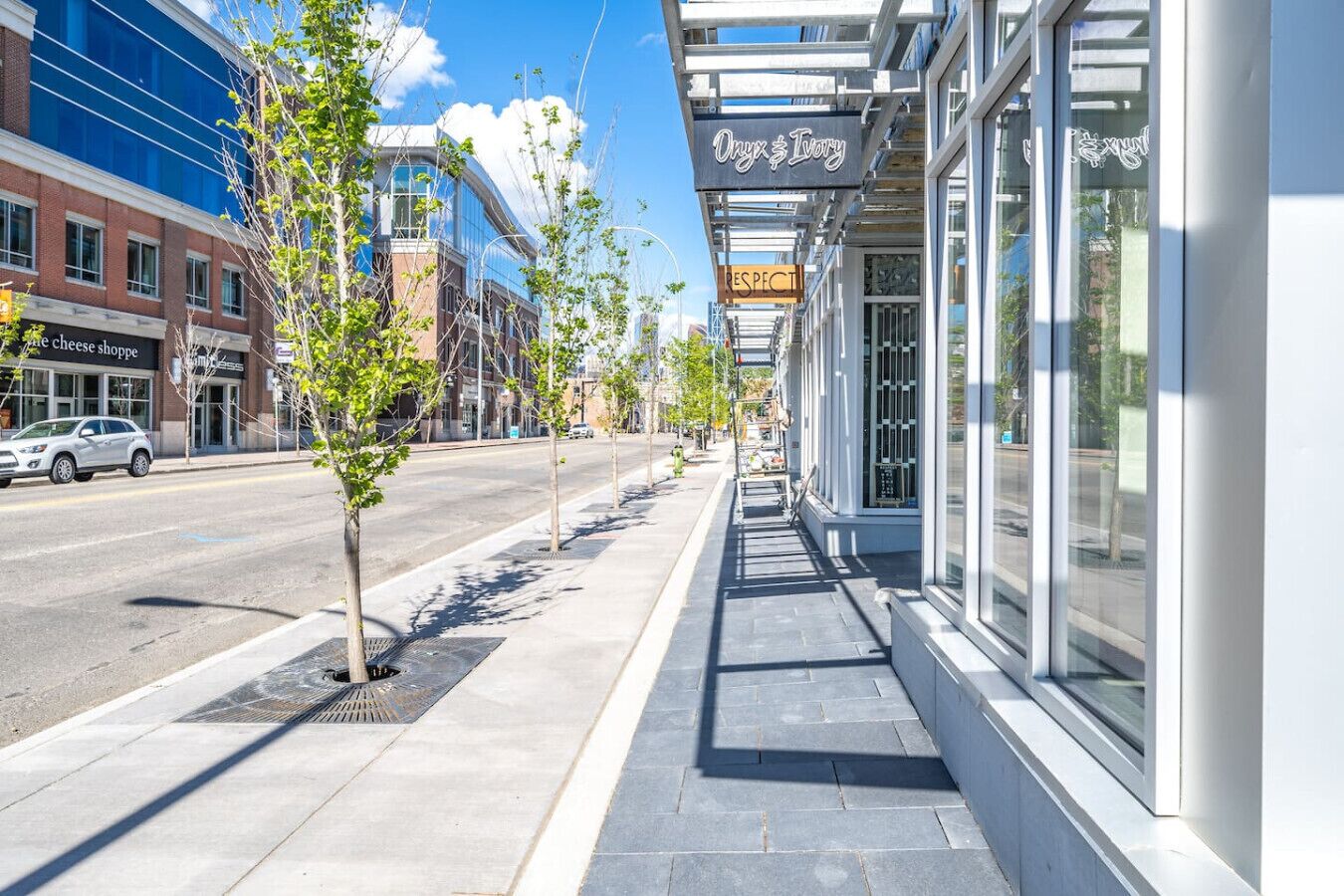 A sidewalk lined with trees and storefronts, including a shop named 'Onyx & Ivory'.