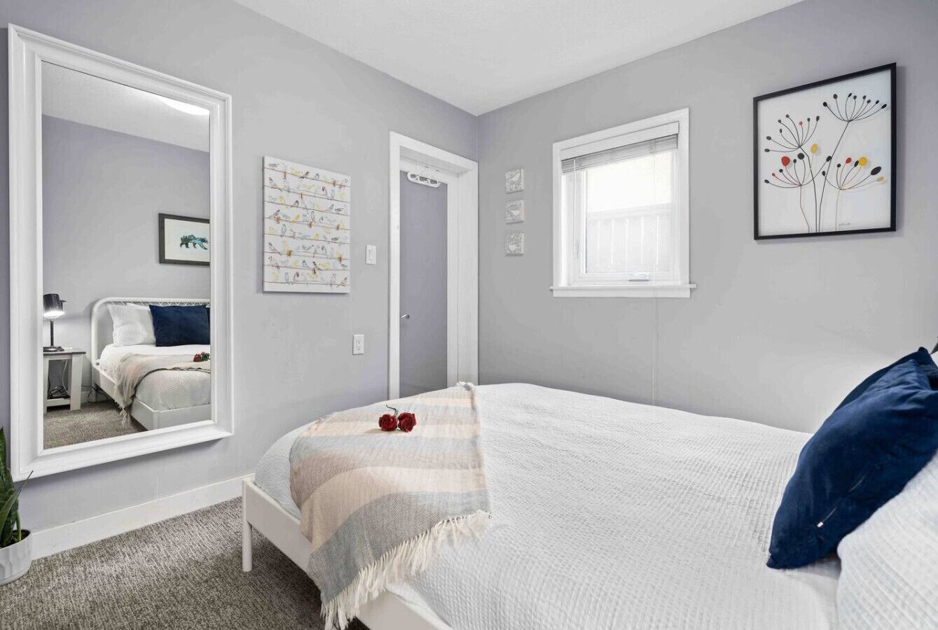 A bedroom with a bed, a large mirror, a window, and a door.