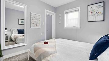 A bedroom with a bed, a large mirror, a window, and a door.