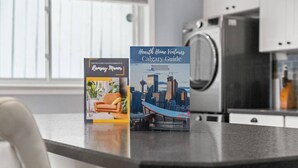 A kitchen counter with two brochures, one titled "Kensington Manor" and the other "Heart Home Ventures Calgary Guide." - Bright and Open Coziness. 10 minutes to Stampede (Calgary)