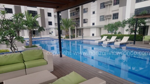 Un área de piscina moderna con sillones de descanso y una terraza de madera.
