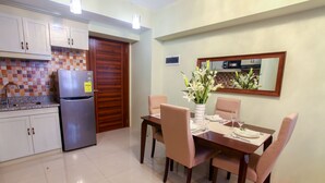 Una cocina con refrigerador, armarios y una mesa de comedor preparada para cuatro personas.