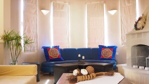 A living room with a blue sofa, a wooden coffee table, and a fireplace. - Niko's Art villa (Chania)