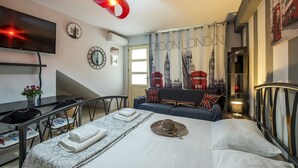 A hotel room with a bed, a desk, a TV, and a sofa. - Niko's Art villa (Chania)