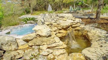 A hot spring surrounded by rocks and greenery.