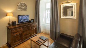 A living room with a wooden cabinet, a television, a remote control, a laptop, and a leather sofa. - OLD TOWN - STUDIO MICHALSKA max 4 pers (Prague 1)