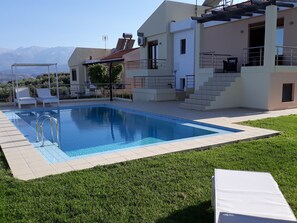 Une maison moderne dotée d’une piscine, d’un patio couvert et offrant une vue sur les montagnes.