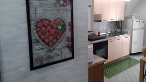 Una cocina con un cuadro con forma de corazón de fresas, un refrigerador blanco y armarios de colores claros.