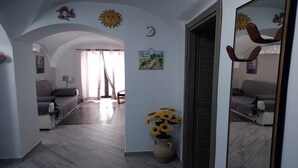 Una habitación con una cama, un sofá, un jarrón con flores y un espejo.