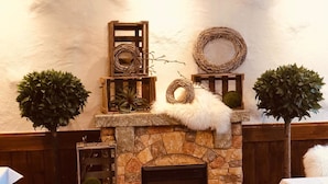 A stone fireplace with a fire, surrounded by wooden shelves with decorative items.