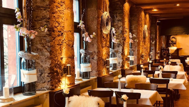 A restaurant with stone walls, white tables, and floral centerpieces.