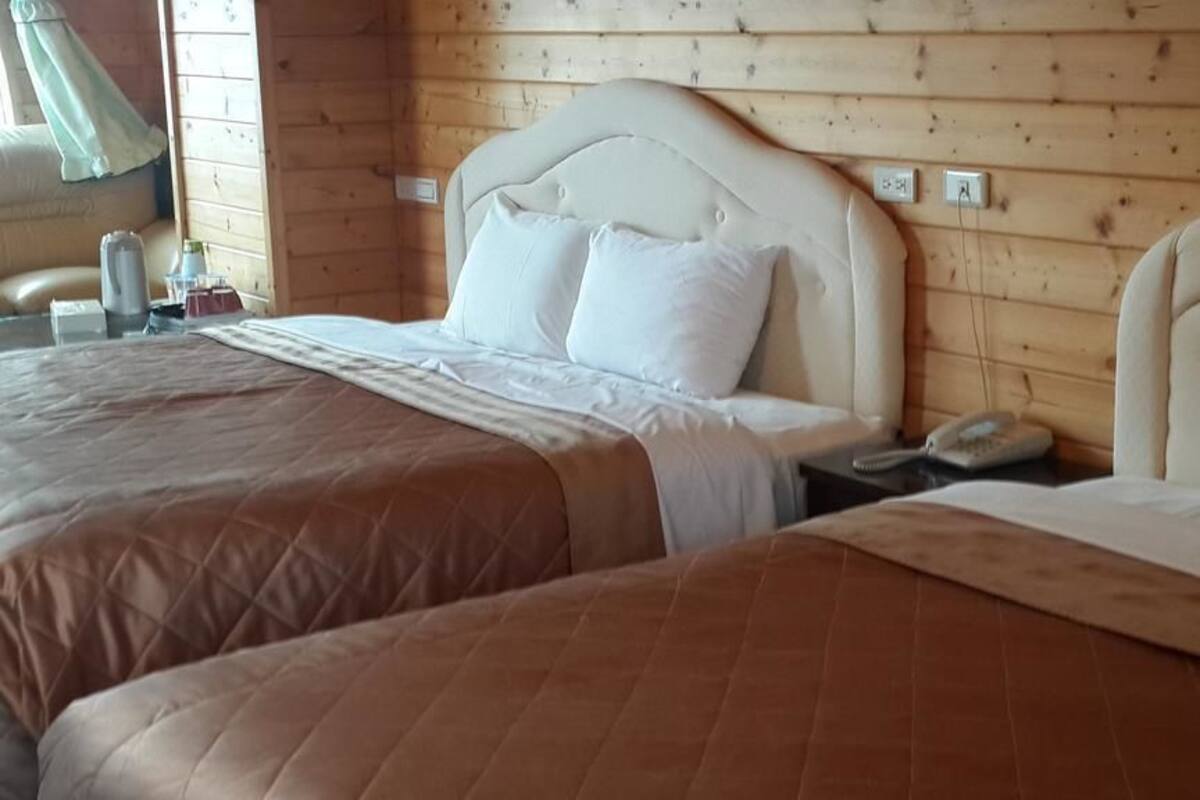 Ein Zimmer mit zwei Betten, jeweils mit Kopfteil, Nachttisch und Lampe.