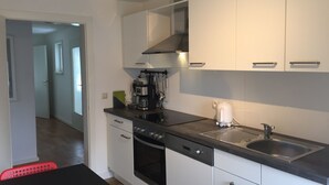 A modern kitchen with white cabinets, a black countertop, a coffee maker, and a dishwasher. - TOP - APPARTMENT - WINTERBERG**** (max. 6 people) Prime location **** (Winterberg)