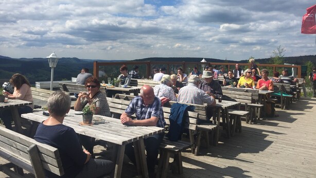 An outdoor dining area with wooden tables and benches, surrounded by a scenic mountain view. - TOP - APPARTMENT - WINTERBERG**** (max. 6 people) Prime location **** (Winterberg)