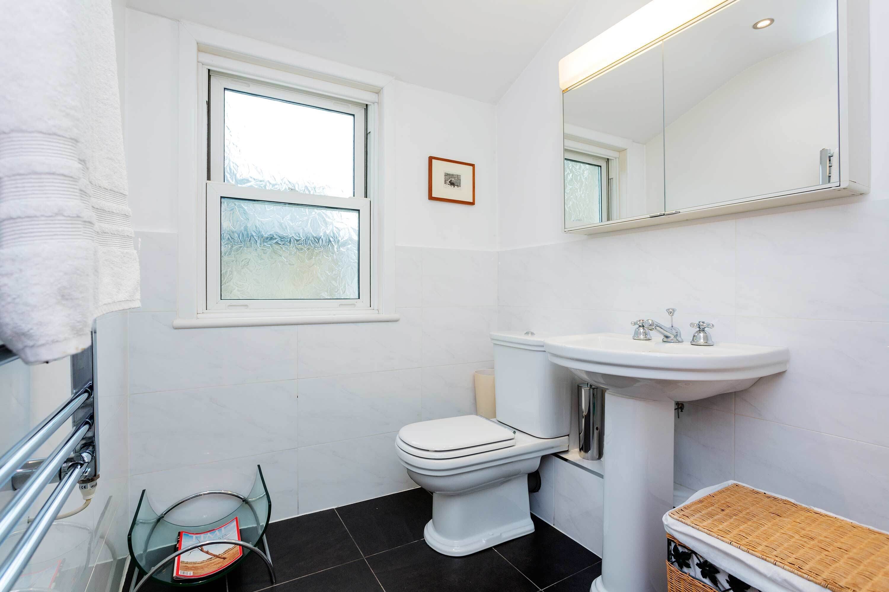 A bathroom with a toilet, sink, and window.